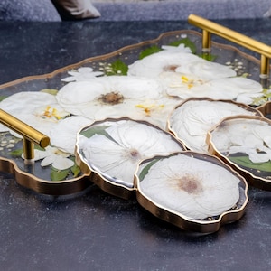 geode tray and coasters made of epoxy resin with preserved flowers and color correction, gold painted edge on black surface