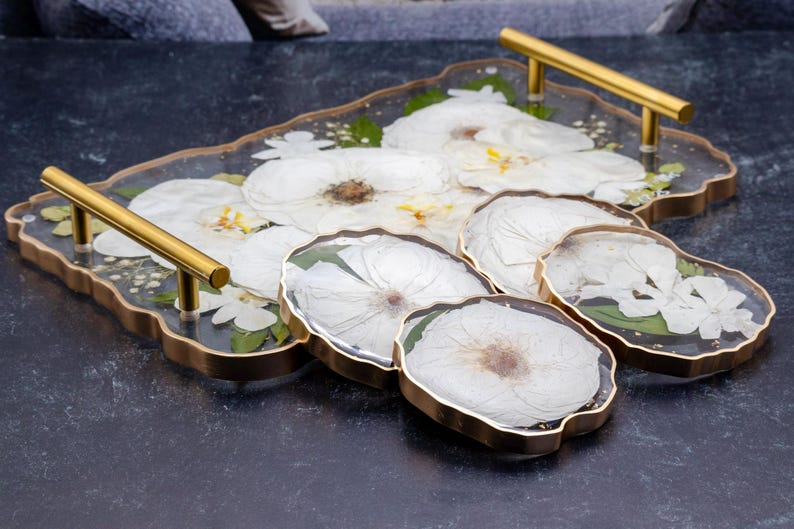 geode tray and coasters made of epoxy resin with preserved flowers and color correction, gold painted edge on black surface