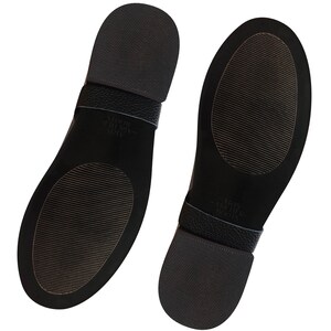 May include: The bottom of two black leather shoes with a textured sole. The shoes have a black leather strap with the text "Allbirds - Wool Runners" printed on them.