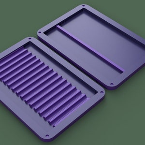 May include: Two purple plastic molds, one with a series of parallel lines and the other with a single line.