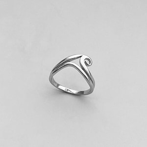 Op de afbeelding: Een zilveren ring met een uniek, abstract ontwerp met een gebogen, open vorm.