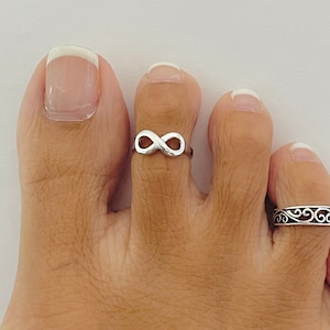Puede incluir: Un anillo de dedo del pie de plata en forma de infinito. El anillo se lleva en el segundo dedo del pie.