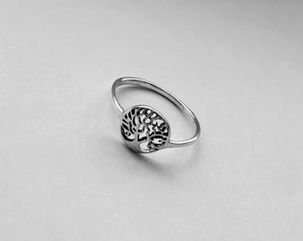 May include: A silver ring with a tree of life design. The ring is delicate and has a simple band.
