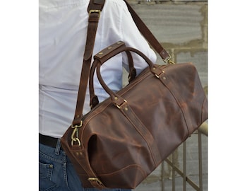 May include: A brown leather duffel bag with a long adjustable shoulder strap and brass hardware. The bag has a top handle and a zippered closure.