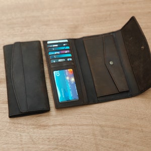 May include: A brown leather wallet with a black leather flap and a card slot. The wallet is open and has several cards inside, including a credit card with the Citi logo.