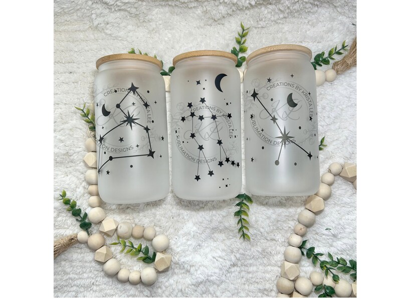 May include: Three frosted glass jars with bamboo lids and black constellation designs. The jars are decorated with a crescent moon, stars, and the text "CREATIONS BY KRISTA LEE SUBLIMATION DESIGNS".