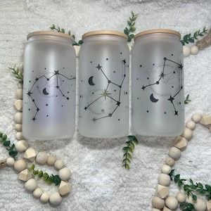 May include: Three frosted glass jars with bamboo lids, each featuring a different constellation design with a crescent moon and stars. The constellations are Aquarius, Virgo, and Gemini. The jars are labelled "CREATIONS BY KRISTINE" and "KRISTINE DESIGNS".