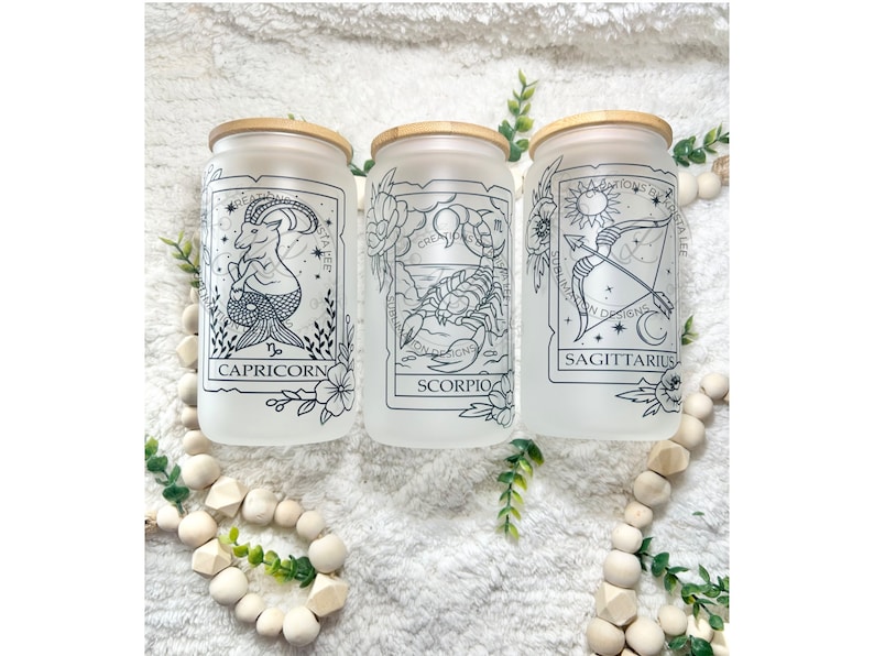 May include: Three frosted glass jars with bamboo lids, each featuring a different zodiac sign: Capricorn, Scorpio, and Sagittarius. The signs are depicted in black line art with floral accents.
