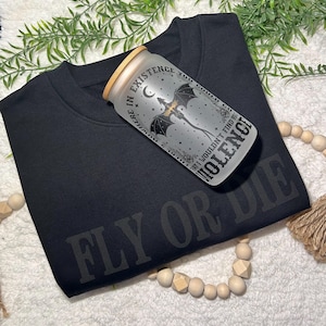 May include: Black t-shirt with the text "Fly or Die" printed in white. A frosted glass jar with a black dragon design and the text "Nowhere in existence you could go that I wouldn't find you... Violence" is on top of the shirt.