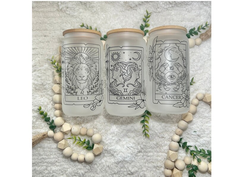 May include: Three frosted glass jars with bamboo lids, each featuring a different zodiac sign: Leo, Gemini, and Cancer. The jars are decorated with black line drawings of the zodiac symbols and have a white background.