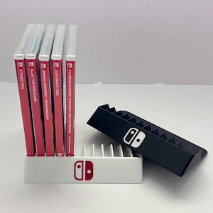 May include: A white and black Nintendo Switch game holder with six game cases. The game cases are red with white text. The holder has the Nintendo Switch logo in red and white.