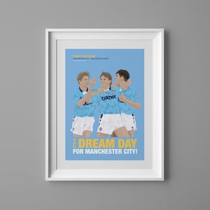May include: A framed illustration of three soccer players celebrating a goal. The players are wearing blue and white uniforms with the word "bother" on the front. The background is light blue with the text "FIRST DIVISION" and "IT'S A DREAM DAY FOR MANCHESTER CITY!" in yellow.