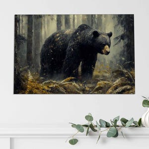 May include: A framed art print depicting a black bear in a forest. The bear, with its dark fur and light brown snout, is the central figure. The background shows tall trees and golden foliage, creating a naturalistic forest scene.