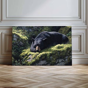 Pode incluir: Impressão em tela de um urso negro descansando sobre uma rocha coberta de musgo. A pelagem escura do urso contrasta com o musgo verde e a folhagem. O focinho do urso é castanho claro. A obra evoca paz e a beleza da natureza.