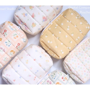 May include: Five rectangular, quilted, zippered pouches labeled Moon Thread Studio Digital Compact Camera Pouches. The pouches feature various floral patterns in soft pastel colors including yellow, pink, blue, and white on fabric surfaces.
