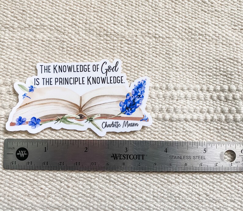 May include: A white sticker with a quote about the knowledge of God by Charlotte Mason. The quote reads "The knowledge of God is the principle knowledge." The sticker features an open book with blue flowers.