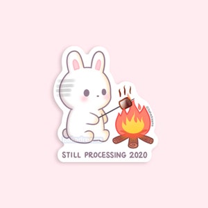 May include: A white bunny sticker with a marshmallow roasting over a campfire. The sticker has the text "STILL PROCESSING 2020" at the bottom. The bunny has pink cheeks and ears. The campfire has orange and yellow flames.
