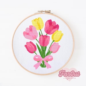 May include: A cross stitch pattern featuring a bouquet of pink and yellow tulips with a pink ribbon bow. The pattern is displayed in a wooden embroidery hoop.