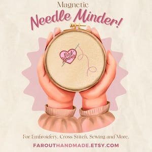 May include: A magnetic needle minder with a pink heart and the text "Girl Power" embroidered on a beige fabric. The needle minder is held by two hands.