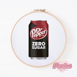 May include: A cross stitch embroidery piece featuring a pixel art design of a Dr Pepper Zero Sugar soda can. The can is rendered in shades of maroon, black, and white, centered within a circular wooden embroidery hoop on white fabric.