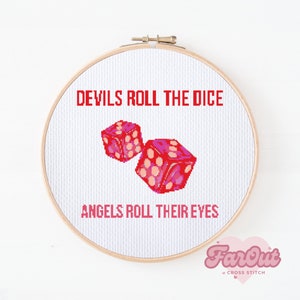 May include: A white embroidery hoop with red text that reads "Devils roll the dice, Angels roll their eyes". Two pink and red dice are embroidered in the center of the hoop.