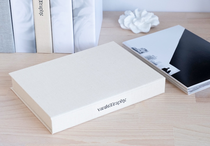 Puede incluir: Una caja rectangular blanca con el texto "vanikography" impreso en la parte delantera. La caja est&aacute; sobre una superficie de madera clara.