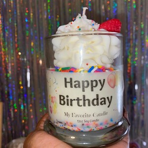 May include: A white soy candle in a glass jar with a frosting design and colorful sprinkles. The candle has a label that says "Happy Birthday" and "My Favorite Candle 12oz Soy Candle".