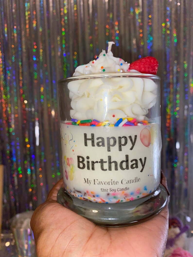 May include: A white soy candle in a glass jar with a frosting design and colorful sprinkles. The candle has a label that says "Happy Birthday" and "My Favorite Candle 12oz Soy Candle".