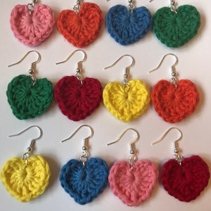 May include: A set of 10 crocheted heart earrings in various colors, including pink, orange, blue, green, yellow, and red. The earrings are attached to silver hooks.