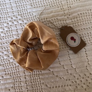 May include: A gold silk scrunchie with a brown tag that says "Rose & Co."
