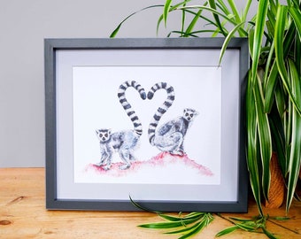 May include: A framed print of two ring-tailed lemurs with their tails forming a heart shape. The lemurs are drawn in black and white with a pink background.