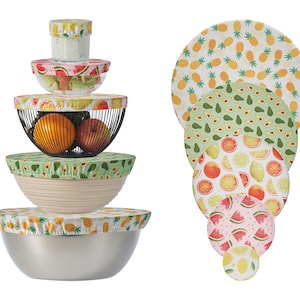Peut inclure: Ensemble de couvercles réutilisables pour bols, ornés de motifs de fruits tels que ananas, avocats, agrumes et pastèques. Les couvercles sont présentés sur des bols de différentes tailles, illustrant leur adaptabilité pour la conservation des aliments.