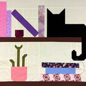 May include: A fabric art piece depicting a bookshelf with a black cat, books, and a potted cactus. The books are various colors and patterns, including pink, purple, and floral prints. The cat is black, and the cactus is green in a pink pot.
