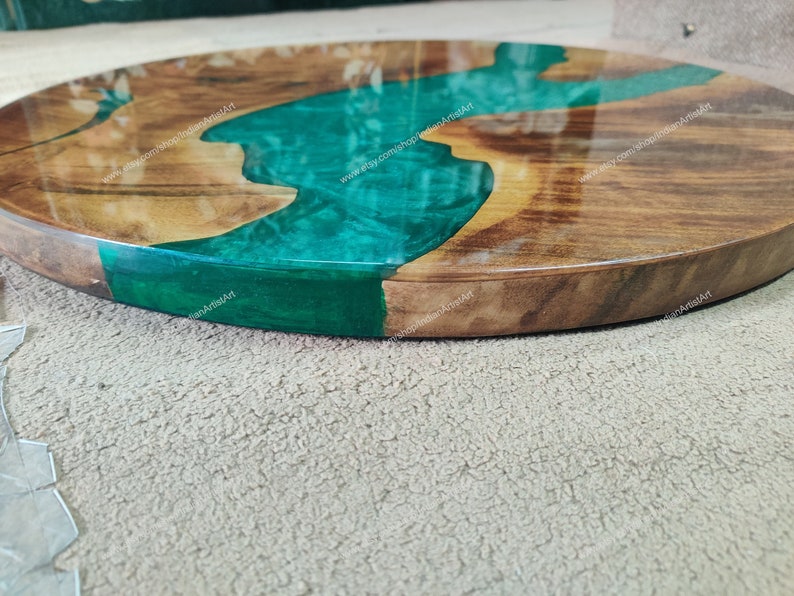 May include: A round wooden serving tray with a green epoxy resin river design. The tray has a natural wood finish and a smooth, polished surface.