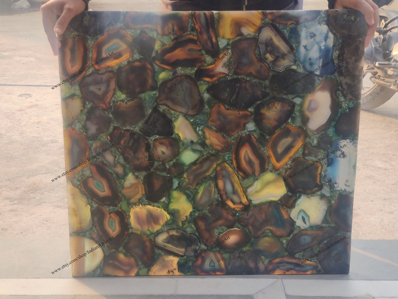 Pu&ograve; includere: Una piastrella quadrata in agata, con un mosaico di fette di agata marrone, verde e giallo. La piastrella ha una superficie lucida ed &egrave; adatta per l'uso come piano da tavolo o decorazione murale.