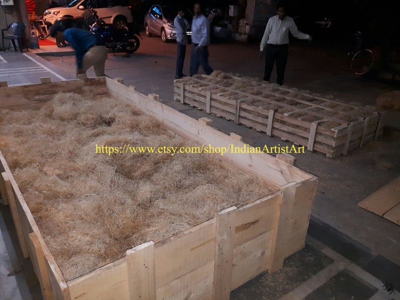 May include: A large wooden crate filled with brown packing material. The crate is sitting on a concrete surface. The text "https://www.etsy.com/shop/IndianArtistArt" is visible on the crate.