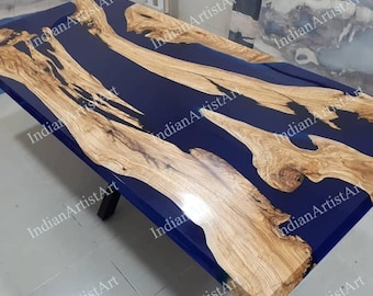Pode incluir: Um tampo de mesa de madeira com um derrame de resina epóxi azul. A resina tem um design fluido, semelhante a um rio. A madeira é de cor castanho claro com um padrão de grão natural. O tampo da mesa é retangular e tem um acabamento liso e polido.