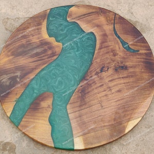 May include: Round wooden table top with a green epoxy river design. The wood is a dark brown colour and the epoxy is a light green colour with swirls. The table top is approximately 61 cm in diameter.