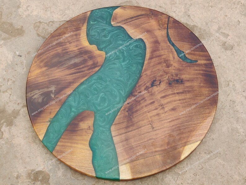 May include: Round wooden table top with a green epoxy river design. The wood is a dark brown colour and the epoxy is a light green colour with swirls. The table top is approximately 61 cm in diameter.