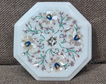 May include: White marble decorative tray with an octagonal shape. The tray features an inlaid floral design with mother-of-pearl, green, red, and blue accents. The floral pattern includes flowers, leaves, and star-shaped elements.