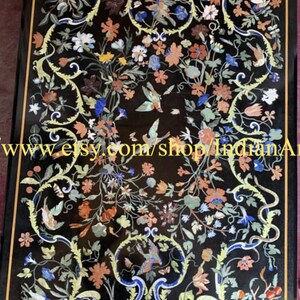 May include: A black marble table top with a floral design inlaid with colorful stones. The design features flowers, leaves, and birds. The table top is approximately 30 inches by 40 inches.