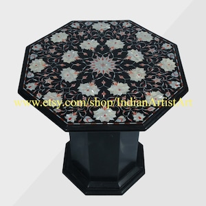 Pode incluir: Mesa octogonal de mármore preto com um design de incrustação floral em branco, vermelho e dourado. A superfície da mesa é incrustada com madrepérola e a base é de mármore preto.