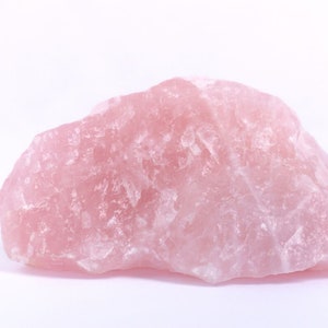 May include: A large, rough, pink rose quartz crystal. The crystal has a natural, unpolished surface.