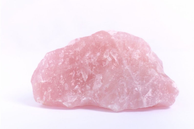 May include: A large, rough, pink rose quartz crystal. The crystal has a natural, unpolished surface.