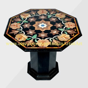 Pode incluir: Mesa octogonal de mármore preto com um design de incrustações florais em tons de marrom, laranja, verde e azul. A mesa tem uma base de madeira preta.