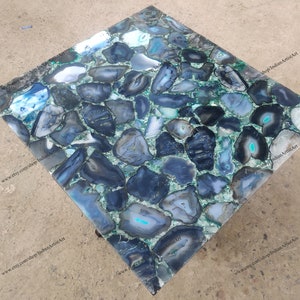 Pu&ograve; includere: Un piano da tavolo quadrato in agata blu e verde. Il piano del tavolo &egrave; composto da molti piccoli pezzi di agata che sono stati tagliati e lucidati. Il piano del tavolo &egrave; posto su una base in metallo.