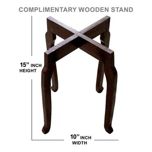 May include: A dark brown wooden stand with a cross-shaped top and curved legs. The stand is 15 inches high and 10 inches wide. The text "COMPLIMENTARY WOODEN STAND" is at the top.