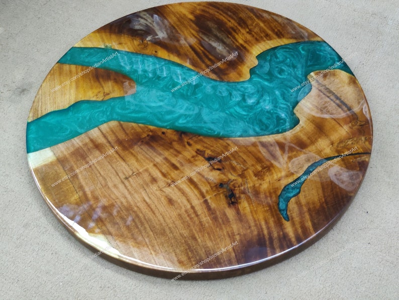 May include: Round wooden table top with a green epoxy resin river design. The wood has a natural brown colour and the resin has a swirling pattern.