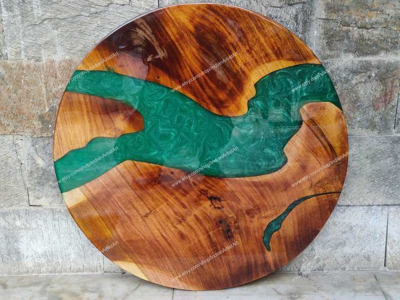 May include: Round wooden table top with a green epoxy resin river design. The wood has a natural brown colour and the resin has a swirling pattern.
