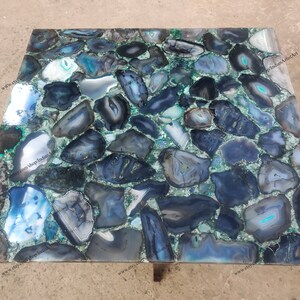 Pu&ograve; includere: Un piano da tavolo quadrato realizzato con fette di agata blu e grigia incastonate in una resina epossidica verde. Il piano del tavolo &egrave; largo circa 76 cm.